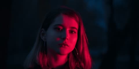 Face lit by magenta and blue neon light at night, an example of the 1980s neon VHS style